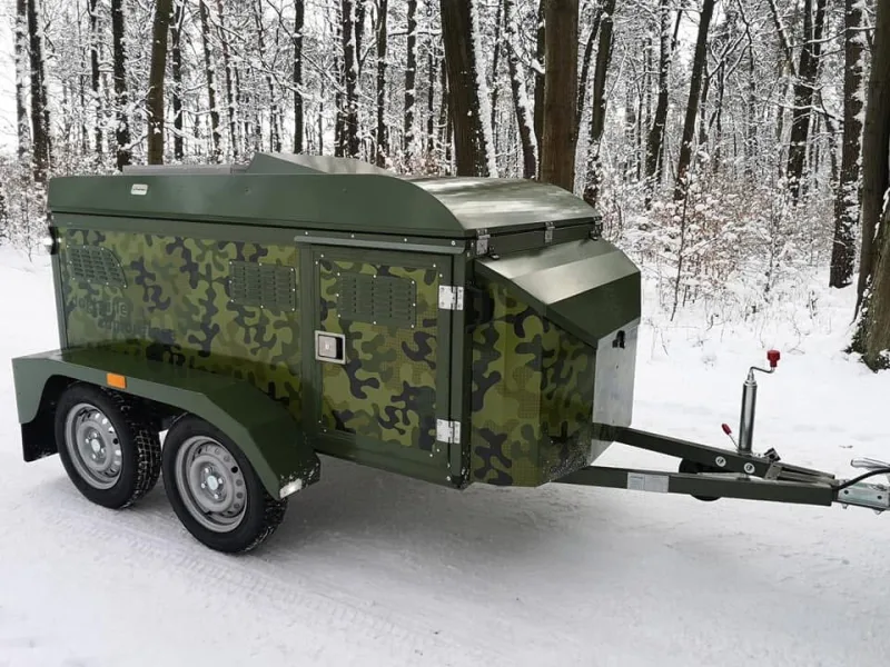 Camouflage-wrapped tandem-axle dog transport trailer in a snowy forest
