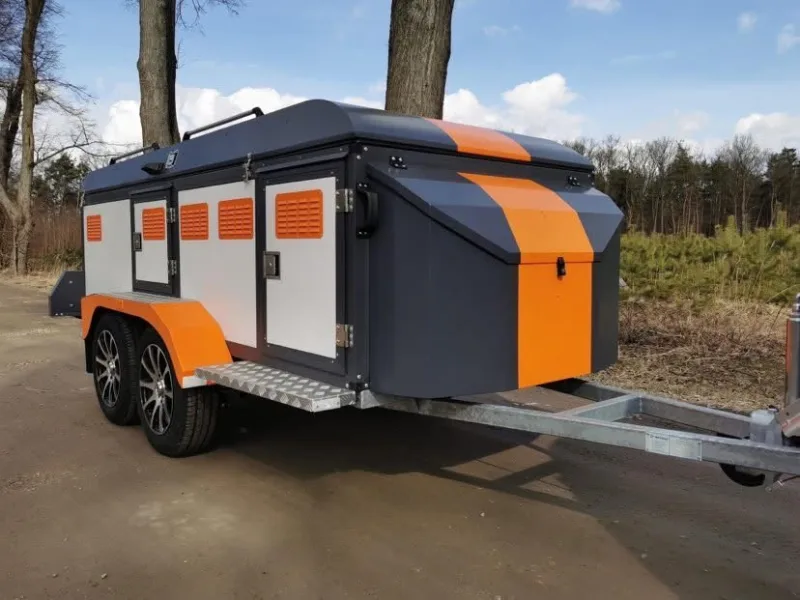 Custom orange and gray dual-axle ventilated dog transport trailer with roof rack