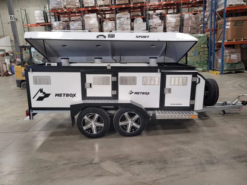METBOX Sport tandem-axle dog trailer with top lid open inside a warehouse